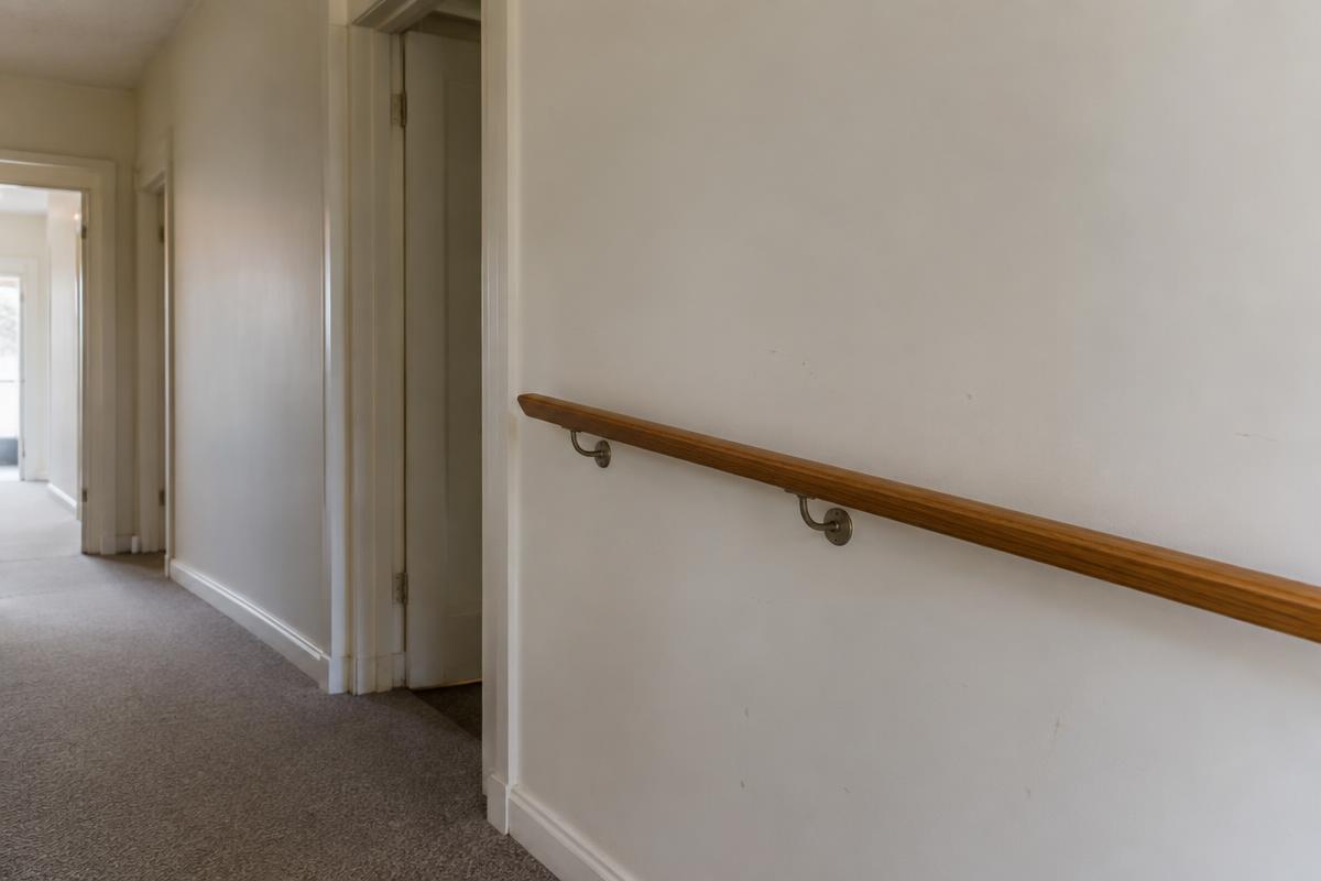 A quiet accessible interior corridor with a timber handrail