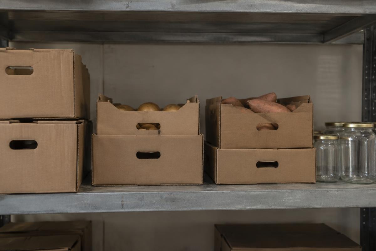An ordinary warehouse shelf with unbranded produce cartons and glass jars