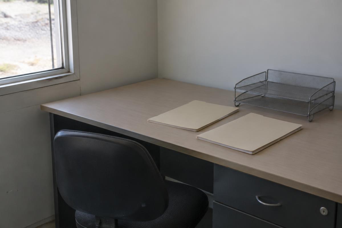 A simple site-office desk with blank folders and a metal in-tray